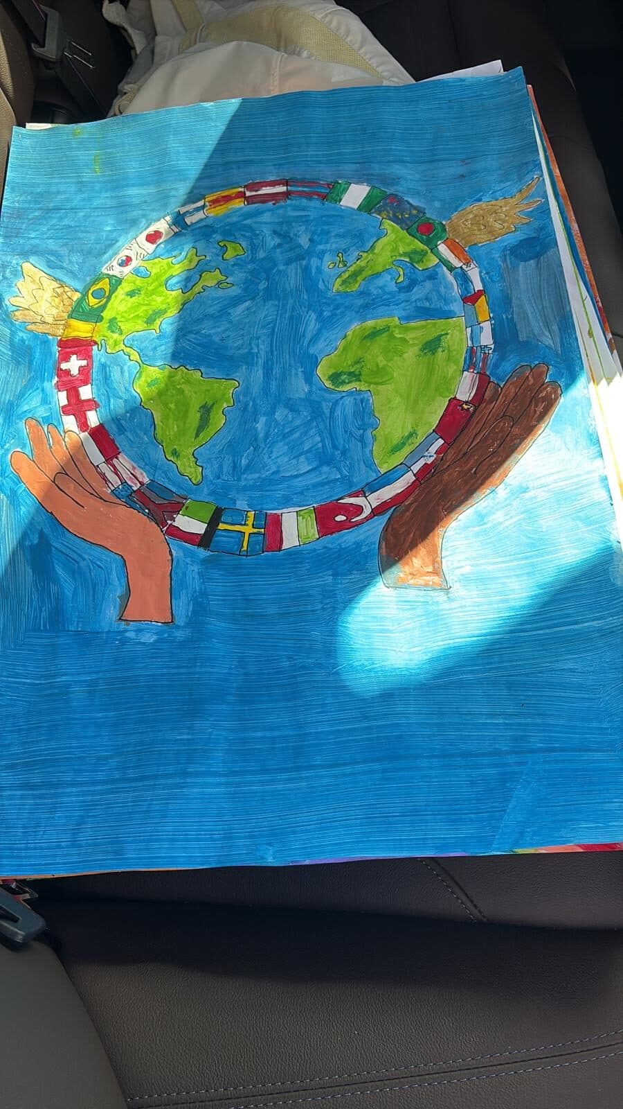 A painted peace poster: two hands hold a blue globe, surrounded by a ring of flags from many countries.